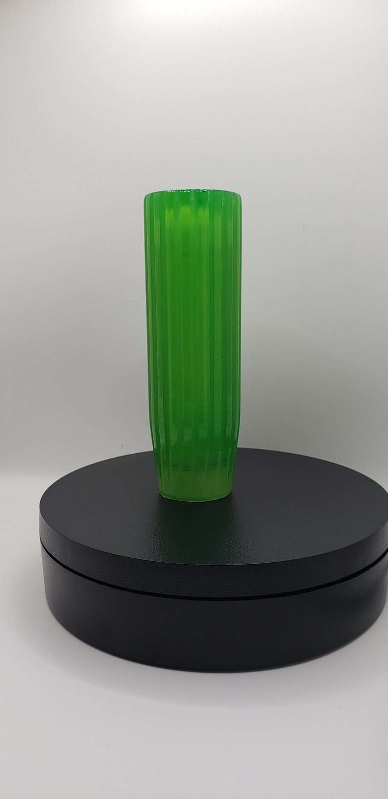 May include: A translucent, vibrant green cylindrical vase featuring a vertical ribbed texture along its entire length. The vase has a straight, uniform profile with a flat top opening and a slightly tapered base, showcasing a bright, semi-transparent finish.