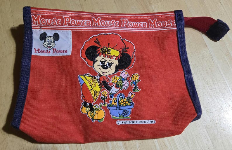 Może przedstawiać: Czerwona pł&oacute;cienna torba z grafiką Minnie Mouse. Torba przedstawia kresk&oacute;wkową Minnie Mouse trzymającą kwiaty i kosz. Tekst "Mouse Power" jest wydrukowany na g&oacute;rze i na małej naszywce. Krawędzie są obszyte niebieską tkaniną.