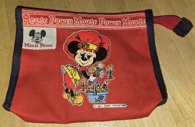 Może przedstawiać: Czerwona pł&oacute;cienna torba z grafiką Minnie Mouse i motywem kwiatowym. Torba ma czarne wykończenie i czerwony uchwyt. Tekst "Mouse Power" jest wydrukowany u g&oacute;ry. Widoczne jest logo Walt Disney Productions.