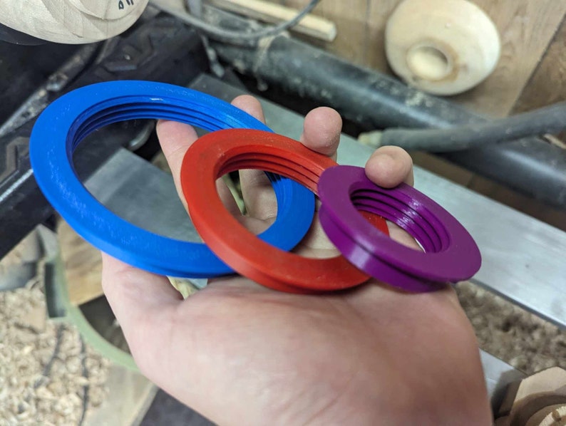 May include: Three different sized rings made of plastic. The rings are blue, red, and purple. The rings are stacked on top of each other.