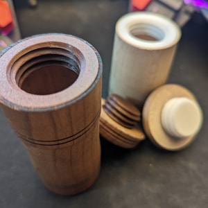 May include: Two wooden containers with lids. One container is brown with a dark wood grain and the other is light brown with a lighter wood grain. Both containers have a white plastic lid.
