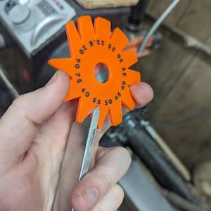 Op de afbeelding: Een oranje kunststof gradenboog met zwarte markeringen voor het meten van hoeken. De gradenboog heeft nummers van 0 tot 90 graden in stappen van 5 graden.