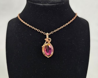 May include: A rose gold necklace with a pink iridescent crystal pendant wrapped in wire.