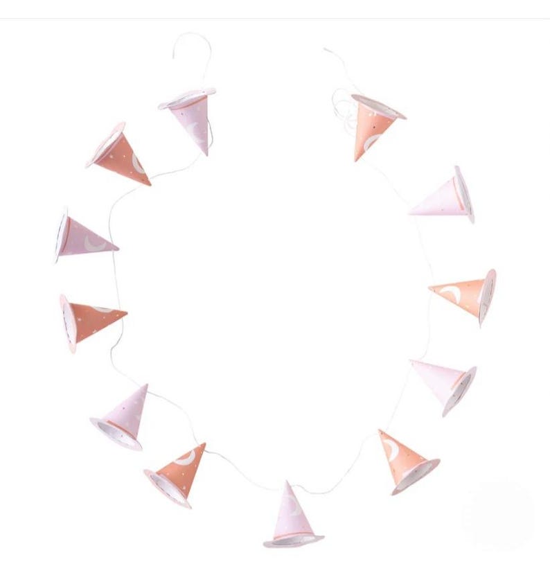 May include: A string of pink and orange witch hats with white crescent moon and star designs. The hats are strung together with white string and are perfect for a Halloween party or a whimsical nursery decor.