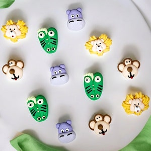 May include: A collection of 10 colorful animal-shaped cake toppers. The toppers are made of fondant and feature a lion, monkey, hippopotamus, and crocodile. The toppers are perfect for adding a fun and whimsical touch to any cake.