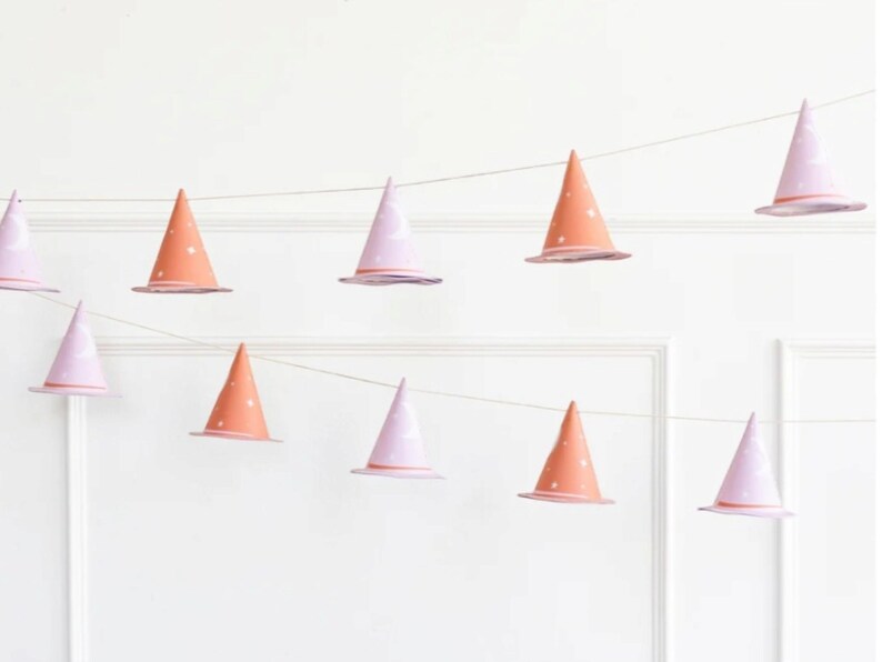 May include: A string of witch hat party decorations with alternating pink and orange hats with white stars. The hats are strung on a white string.