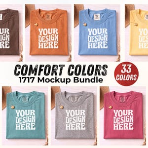 May include: A collection of six folded crew neck t-shirts in brown, orange, blue, yellow, teal, gray, and pink, each featuring the white text 'YOUR DESIGN HERE' on the front. The image includes the text 'COMFORT COLORS 1717 Mockup Bundle' and '33 COLORS'.