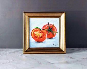 May include: A framed painting of two red tomatoes, one cut in half, on a white background. The painting is signed "Kaje".