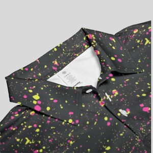Close-up of the collar area of the black polo shirt, showing white inner label and white buttons.