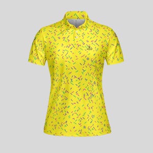 A yellow women's golf polo shirt with a colorful sprinkle pattern on a plain background.
