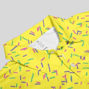 Close-up view of the collar and white inner label of the yellow sprinkle polo shirt.