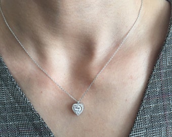 May include: A silver chain necklace with a heart-shaped pendant featuring a clear crystal surrounded by smaller crystals.