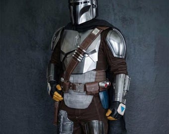 May include: A detailed costume of a Mandalorian warrior. The armor is primarily silver with brown and black accents. The helmet is a polished silver, and the costume includes a brown leather belt with pouches and a holster.