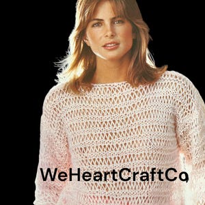 May include: A woman with long blonde hair is wearing a white crocheted sweater. The sweater has a loose, open weave and is see-through. The woman is looking at the camera with a serious expression.