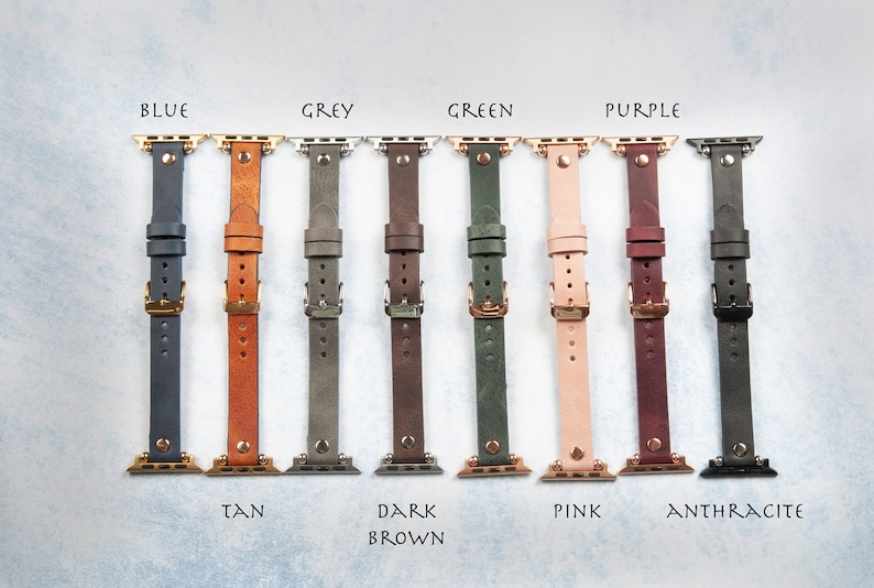 May include: A collection of leather watch bands in various colors, including blue, tan, grey, dark brown, green, pink, purple, and anthracite. Each band is shown with gold-colored hardware and labeled with its respective color name. The bands are designed for smartwatches.