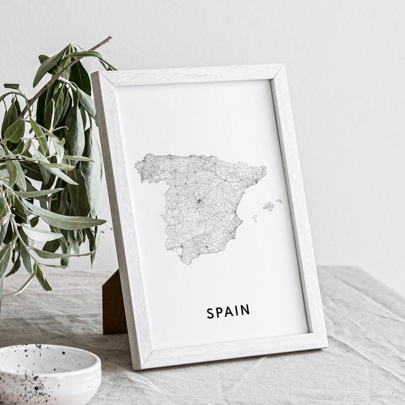 May include: A black and white line art print of a map of Spain in a white frame. The word "SPAIN" is printed in black below the map.