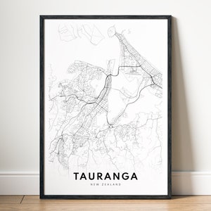 Op de afbeelding: Een zwart-witte kaartprint van Tauranga, Nieuw-Zeeland, in een zwart frame. De kaart toont de straten en waterwegen van de stad.