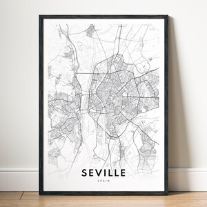 Puede incluir: Una impresión enmarcada en blanco y negro del mapa de Sevilla, España. El mapa detallado de la ciudad muestra calles, vías fluviales y áreas urbanas. El nombre de la ciudad y el país están impresos en la parte inferior.
