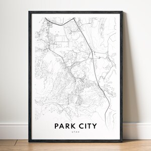 May include: A framed black and white map print of Park City, Utah. The map features detailed street and topographic lines, with the city name and state printed in a clean, modern font at the bottom.