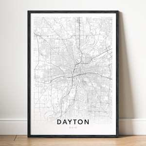 May include: A framed black and white map print of Dayton, Ohio. The detailed map shows the city's streets and waterways. The city name and state are printed in a clean, modern font at the bottom of the print.