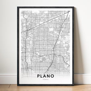 May include: A framed black and white map print of Plano, Texas, featuring a detailed grid of city streets, highways, and urban infrastructure. The text PLANO is printed in bold black capital letters above the smaller text TEXAS at the bottom.