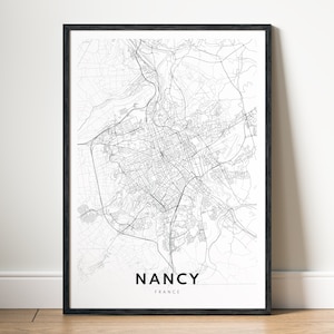 May include: A black and white map print of Nancy, France, in a black frame. The map shows the city's streets and waterways. The city name "NANCY" and "FRANCE" are printed below the map.