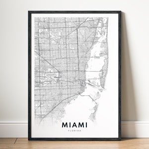 May include: Black and white map print of Miami, Florida in a black frame. The map shows the city streets and the coastline.