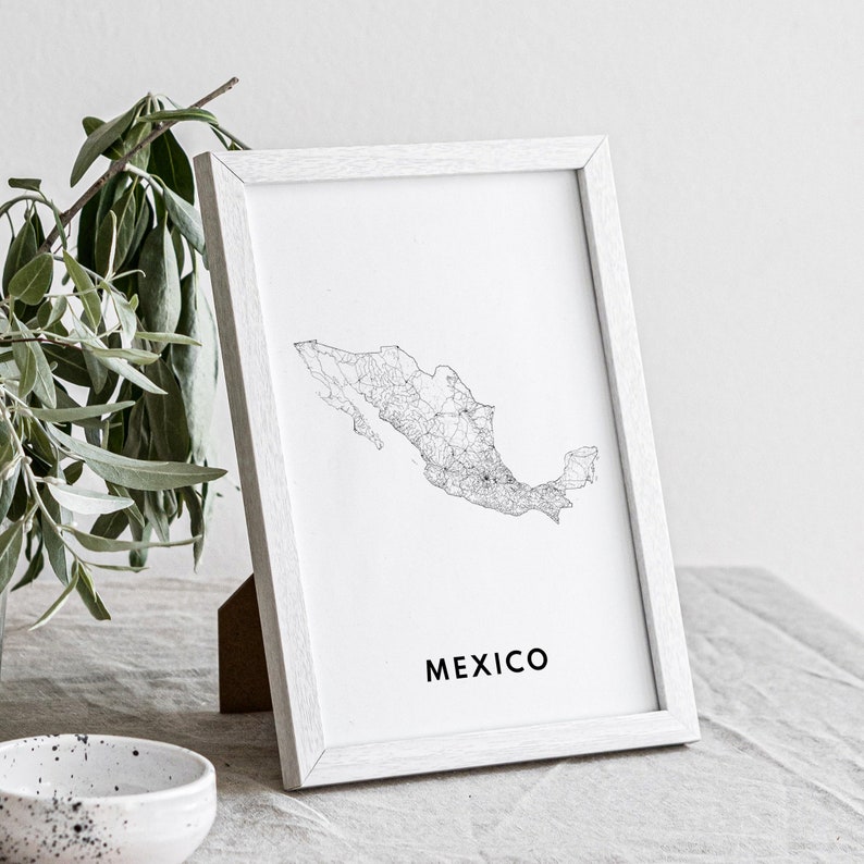 May include: A framed print of the Mexico map in black and white. The map is detailed with lines representing roads and cities. The word "MEXICO" is printed in a black, sans-serif font below the map. The frame is white.