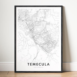 May include: A framed black and white map print of Temecula, California. The map is a detailed line drawing of the city's layout, including roads and buildings. The city's name is printed in a simple font at the bottom of the print.