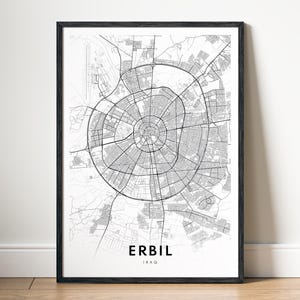 May include: A framed black and white map print of Erbil, Iraq. The map details the city's structure, featuring circular roads and radial streets. The city's name and country are printed in a simple font at the bottom of the print.