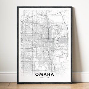 Puede incluir: Una impresión de mapa en blanco y negro de Omaha, Nebraska, en un marco negro. El mapa muestra las calles de la ciudad y sus principales puntos de referencia.