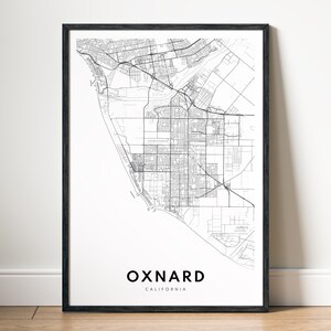 Może przedstawiać: Oprawiony czarno-biały wydruk mapy Oxnard, Kalifornia. Szczegółowa mapa miasta przedstawia ulice i infrastrukturę. Słowo "OXNARD" jest wyśrodkowane na dole, z napisem "CALIFORNIA" poniżej. Wydruk jest wyświetlany na białej ścianie.