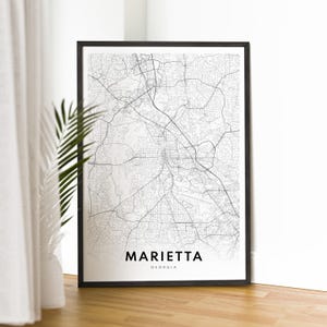 May include: Black and white map print of Marietta, Georgia in a black frame. The map shows the city streets and roads.