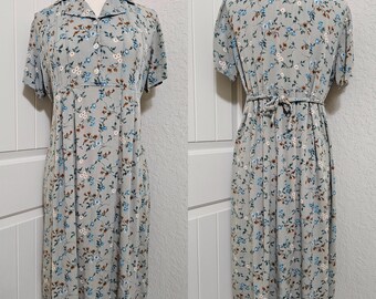 May include: A light blue dress with a floral print. The dress has a collared neckline, short sleeves, and a tie at the waist.