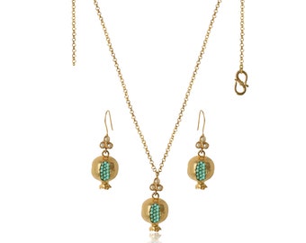 Può includere: Un set di collana e orecchini in oro con un design a forma di melograno. Il ciondolo e gli orecchini presentano una pietra turchese all'interno di un melograno d'oro.