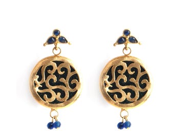 Könnte beinhalten: Ein Paar goldene Ohrringe mit einem schwarzen Filigranmuster und blauen Edelstein-Akzenten.