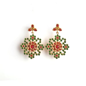 以下が含まれることがあります： 赤と緑の花柄の金色のイヤリングのペア。イヤリングは金属製で、繊細で複雑なデザインです。