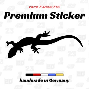 Könnte beinhalten: Schwarzer Aufkleber mit einer Eidechsen-Silhouette auf weißem Hintergrund. Der Aufkleber trägt den Text "Premium Sticker" und "race FANATIC" in Rot. Der Aufkleber ist "handmade in Germany".