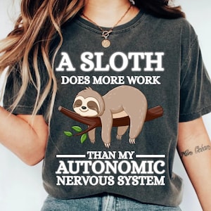 May include: Dark gray t-shirt with the text "A SLOTH DOES MORE WORK THAN MY AUTONOMIC NERVOUS SYSTEM." A cartoon sloth is illustrated on a branch. The shirt is a relaxed fit.