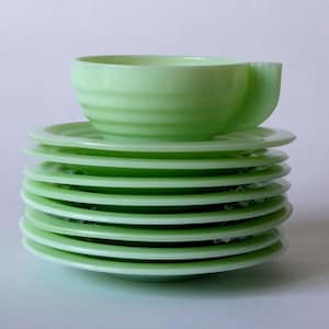Könnte beinhalten: Ein Stapel von acht hellgrünen Glasplatten mit einer passenden Tasse. Die Tasse befindet sich oben auf dem Stapel der Teller. Die Tasse und die Teller haben ein geripptes Design. Das Set ist hellgrün.