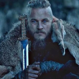 May include: A person with a shaved side hairstyle and a full beard, wearing a textured fur garment over the shoulders. A metallic sword with an intricate, patterned hilt and a polished blade is held upright in front of the chest.