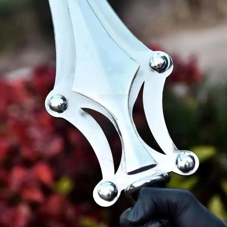 Op de afbeelding: Een zilverkleurig metalen zwaardblad met een centrale richel en een decoratieve pareerstang met vier afgeronde, gepolijste metalen klinknagels. Het blad heeft een symmetrische, puntige vorm met gebogen uitsparingen aan beide zijden.
