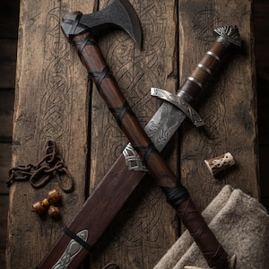 May include: A battle axe with a dark metal head and a wooden handle wrapped in black leather strips, crossed with a sword featuring a patterned metal blade, a wooden grip with silver accents, and a pommel shaped like a small antler.