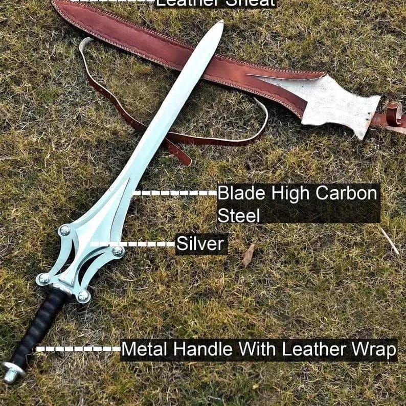 Op de afbeelding: Een zilverkleurig zwaard met een lemmet van koolstofrijk staal, een metalen handvat met een lederen wikkeling en een bruine lederen schede. Tekstlabels op de afbeelding identificeren de onderdelen als Leather Sheath, Blade High Carbon Steel, Silver en Metal Handle With Leather Wrap.