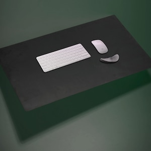 Op de afbeelding: Een zwarte bureau mat met een wit draadloos toetsenbord en een witte muis. De muis ligt op een grijze polsrust.