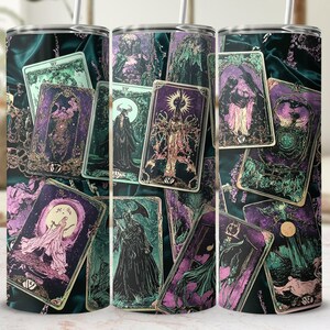 Puede incluir: Tres vasos de acero inoxidable con un diseño negro, verde y morado que presenta cartas de tarot. Las cartas tienen detalles dorados y representan varias figuras y símbolos.