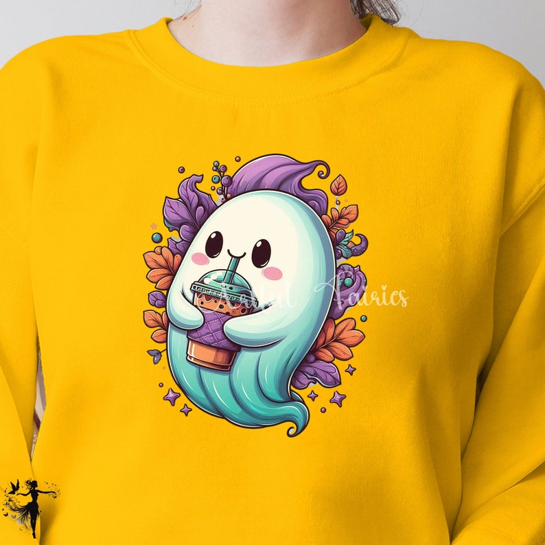 May include: Yellow sweatshirt featuring a cartoon ghost holding a bubble tea. The ghost is white with a teal body, surrounded by purple and orange floral accents. The design includes stars and a purple swirl.