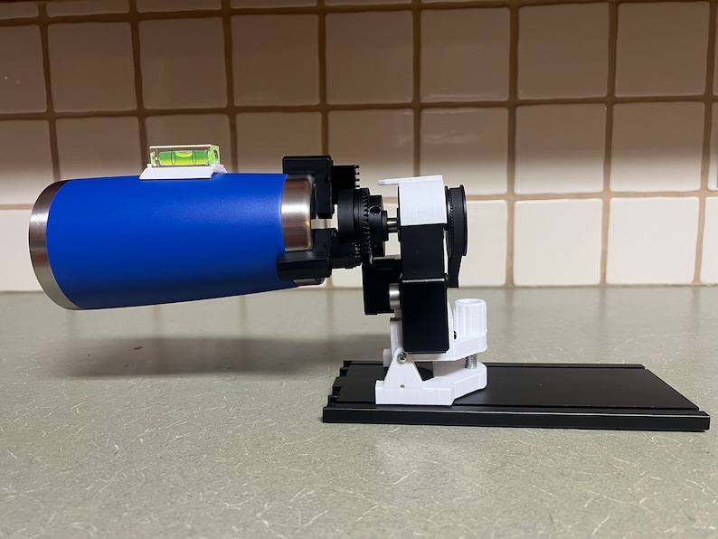 Peut inclure: Une bouteille d'eau bleue et argent&eacute;e mont&eacute;e sur un support imprim&eacute; en 3D blanc et noir avec un niveau attach&eacute; &agrave; la bouteille.