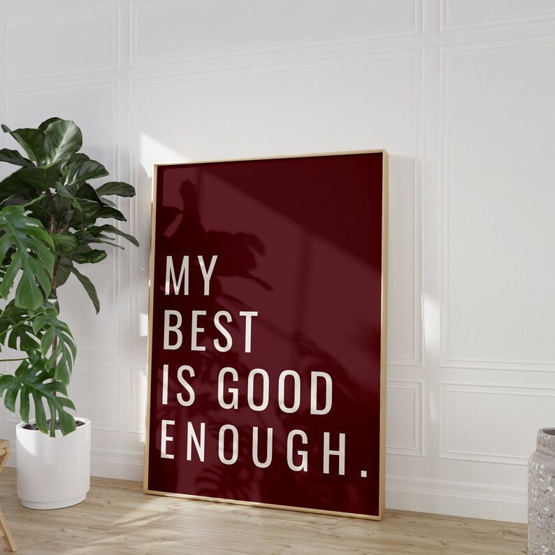 Może przedstawiać: Burgundowy plakat w złotej ramie z napisem "MY BEST IS GOOD ENOUGH." w białych literach.