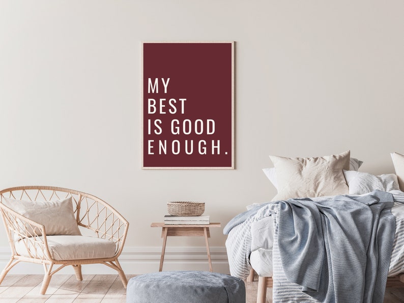 Może przedstawiać: Granatowy plakat z białym tekstem, kt&oacute;ry brzmi "My best is good enough." Plakat wisi na białej ścianie w sypialni. Jest tam wiklinowe krzesło z białym poduszką, drewniany stolik z książkami i wiklinowym koszem oraz ł&oacute;żko z biało-szarym wzorzystym kocem i niebieskim narzutem.